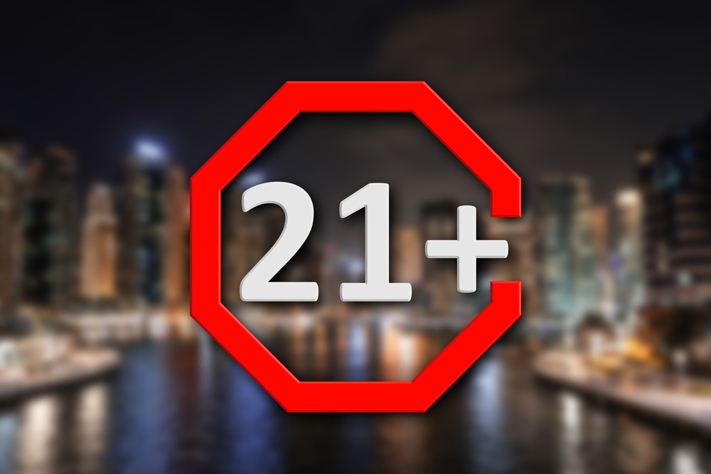 Age limit sign 21+ years and blurred view of night city