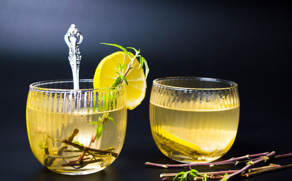 Cannabis tea with marijuana stem and lemon in glass cup