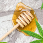 Honey with a honey dipper and Cannabis leaves