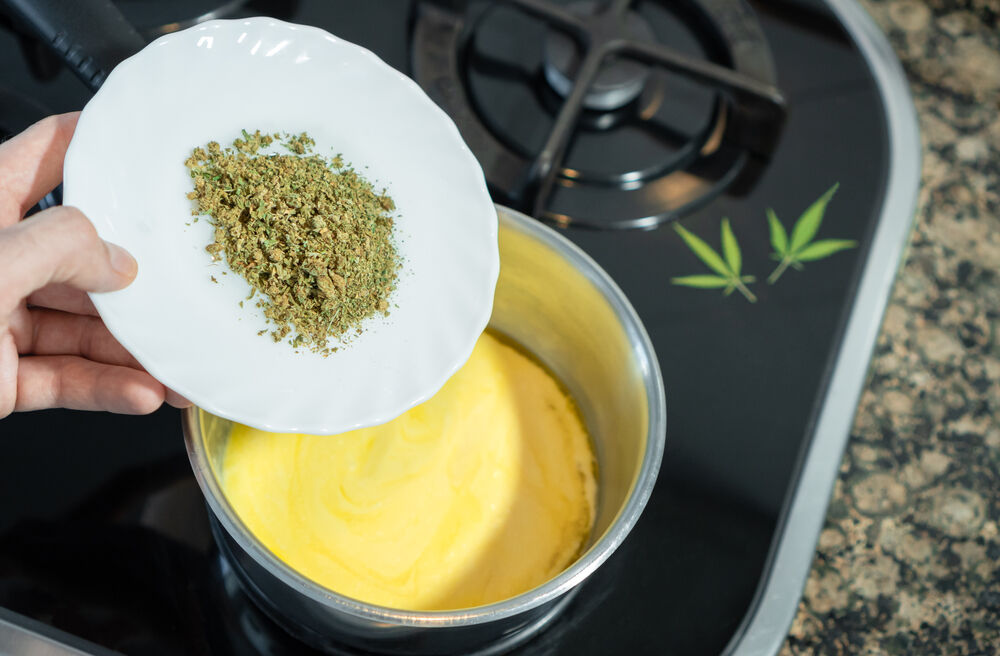 Mixing crushed cannabis with melted butter to prepare marijuana butter