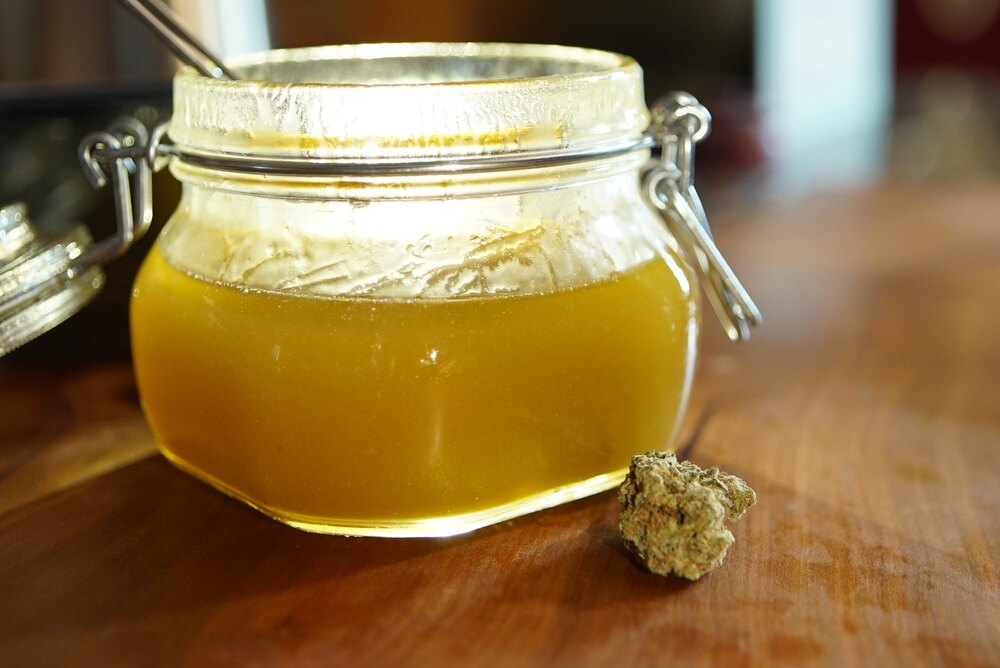 honey in a glass jar with cannabis bud