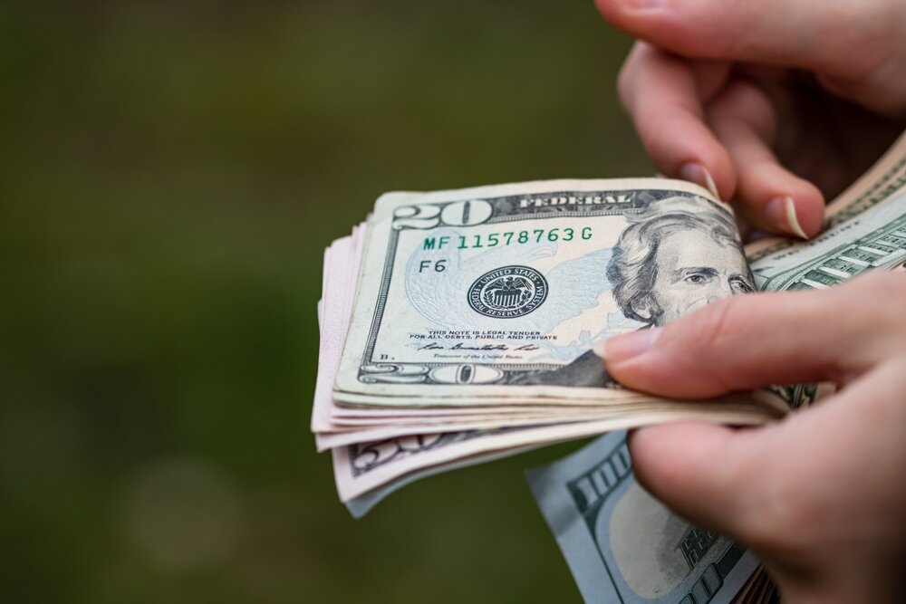 a person hand holding US dollars