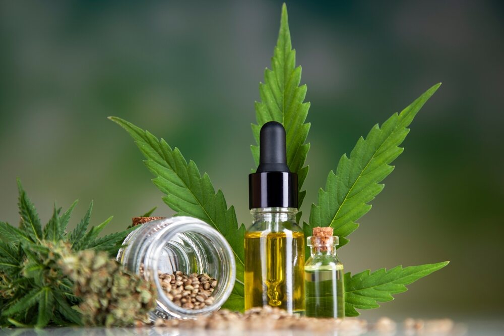 CBD oil with cannabis seeds and leaf in the background