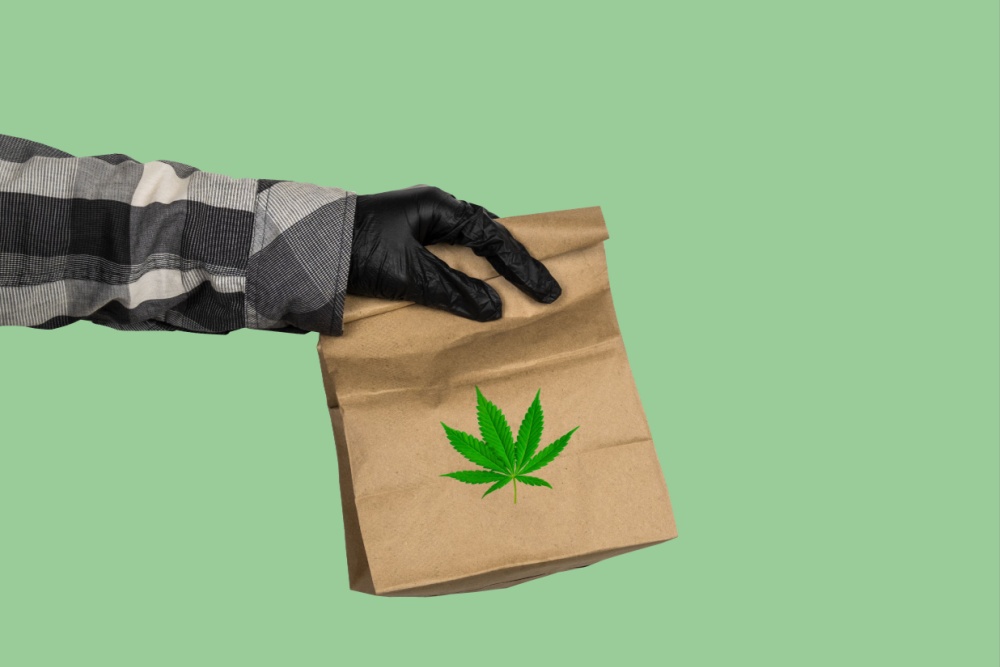 a persons hand holding out a cannabis logo brown bag